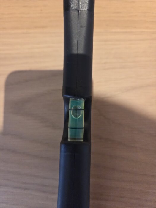 Vattenpass på parkettgolv visar en lutning med bubblan inte centrerad.