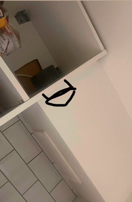 Ett vitt skåp med ett uppåtriktat rör och ett don. En ritad figur markerar platsen och riktningen för donet inuti skåpet.
