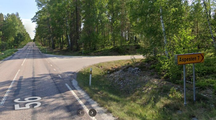 Vägkorsning med skylt mot Aspesten 7, omgiven av skog och natur.