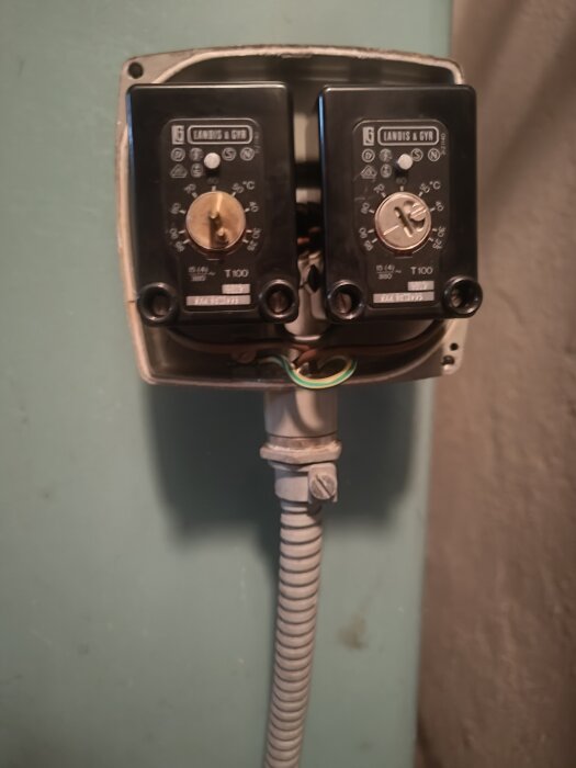 Två termostater monterade på en vägg med synliga kablar och temperaturskala, används för att koppla in en pellx brännare i en CTC 265b.