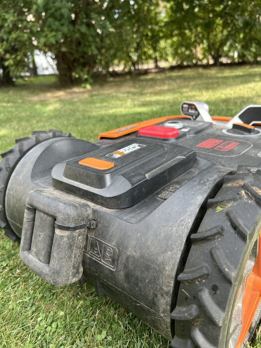 Robotgräsklippare med fastsatt blyvikt för stabilitet, fäst med buntband. Synliga instruktioner för borrning.