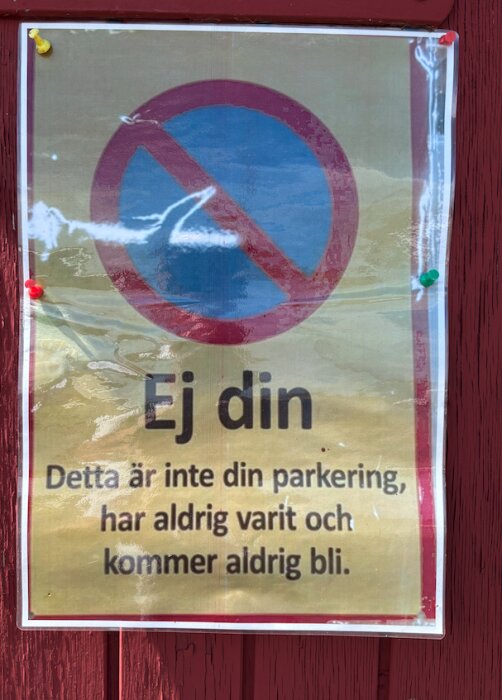 Parkeringsskylt med texten "Ej din. Detta är inte din parkering, har aldrig varit och kommer aldrig bli" mot en rödmålad vägg.