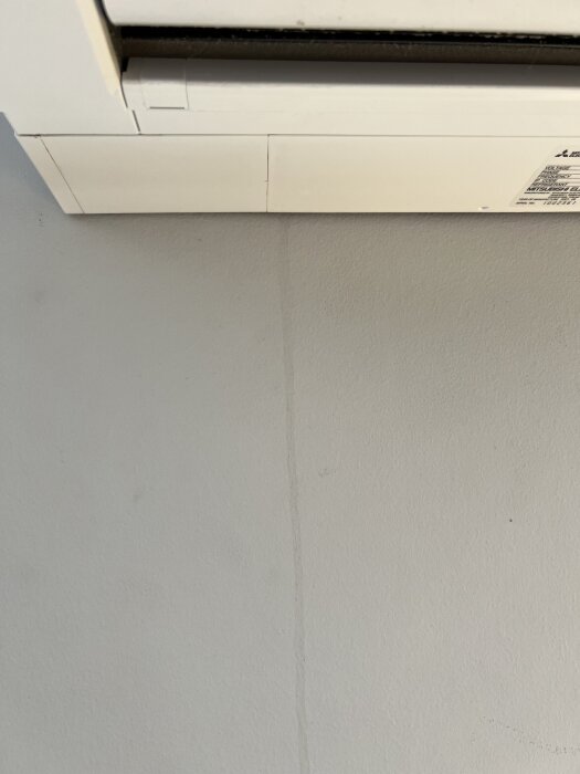Innedel av en Mitsubishi Hero luftvärmepump med kondensstreck på väggen som tyder på mögelproblem.