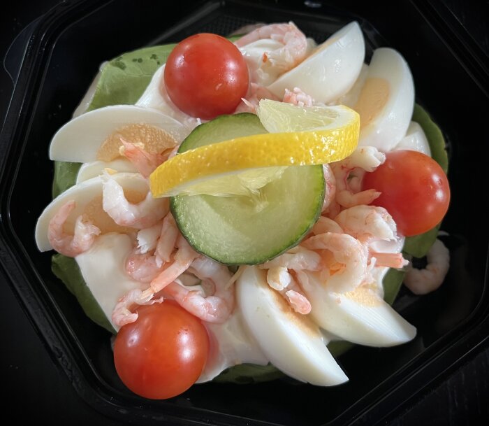 RÀkmacka med rÀkor, kokt Àgg, körsbÀrstomater, gurkskiva och citronskiva pÄ salladsbÀdd.