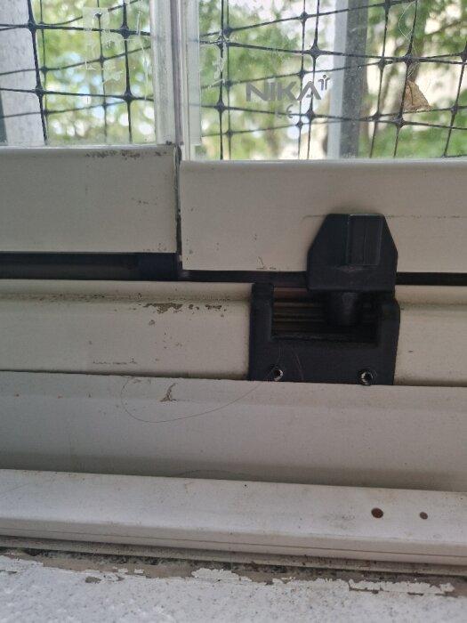 Glasdörr från Nika med al-list och synligt fäste vid tappen som har sjunkit. Dörren verkar justerad efter försök att skruva ur skruvar.