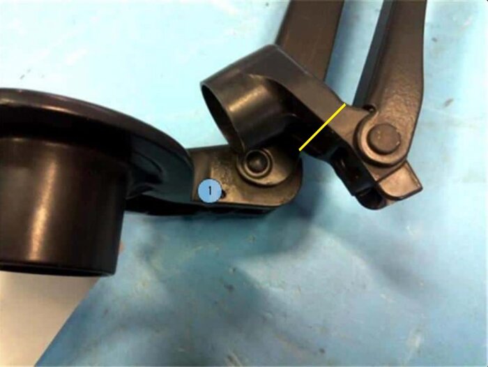 Toyota Ractis vindrutetorkare med markerad spricka där plasten gått av, reparerad med superlim och bakpulver, markerad med gult streck.