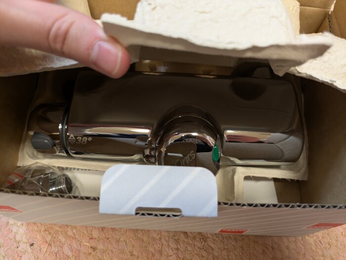 Duschblandare Oras Optima 5164 i kartong, delvis inpackad i papper, visas i ett garage under rensning.