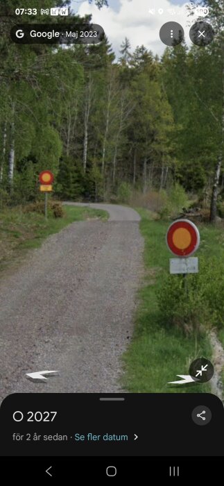 Grusväg med två skyltar som förbjuder fordonstrafik, omgivna av skog.