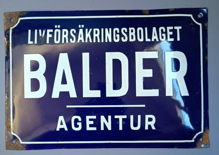 Emaljskylt för livförsäkringsbolaget Balder, med text "Balder Agentur" i vita bokstäver på blå bakgrund, verksam till 1960.