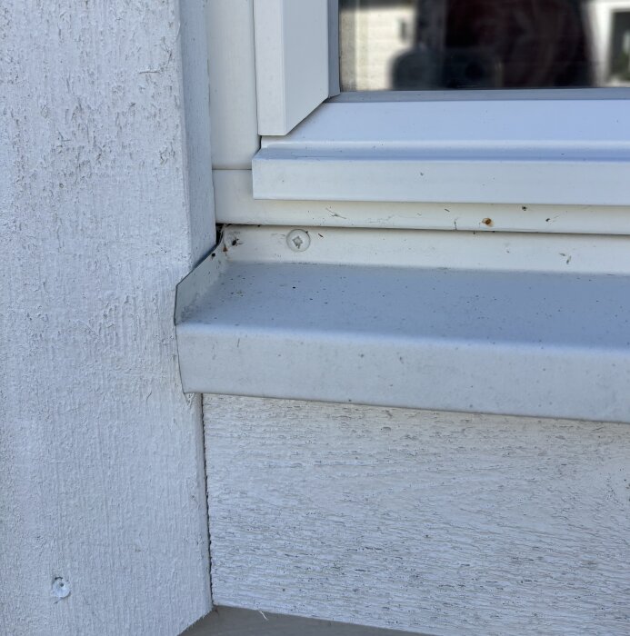 Ikkunan kulma ja vesilista, jossa näkyy likaa ja ruuvinreikä.