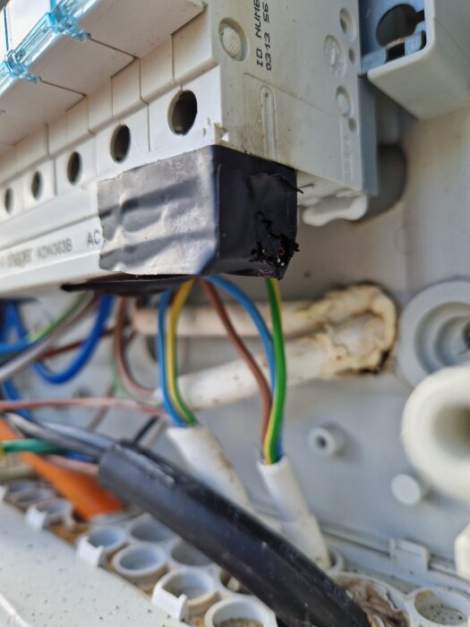 En bild av en elcentral på en yttervägg där en del av installationen ser skadad ut med brännmärken, vilket kan indikera en elbrand.