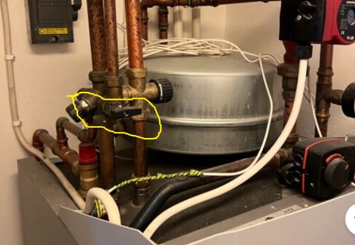 VVS-installation med flera kopparrör, avstängningsventiler och en cirkulationspump vid en värmepanna i källarmiljö.