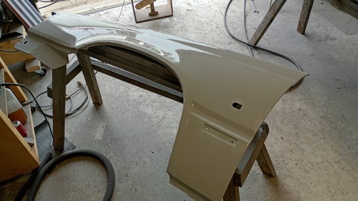 Nymålad bilskärm placerad på bockar i ett garage.