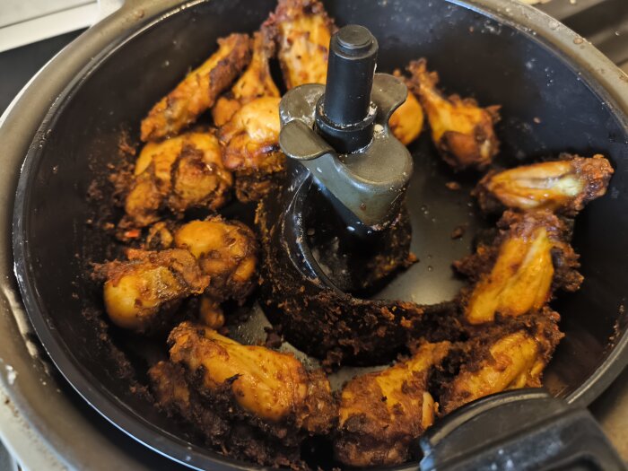 Kycklingvingar tillagade i en airfryer, gyllenbruna och krispiga efter att ha marinerats i brine över natten, redo för servering.