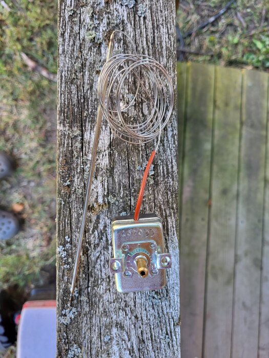 Okapslad rökgastermostat med rör och sladd för panelmontage, placerad på en träyta.