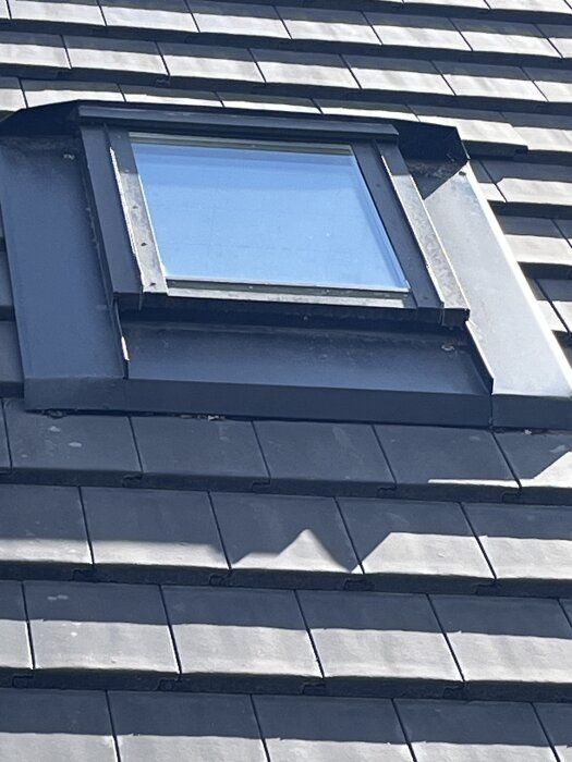 Takfönster på ett tak med mörka plattor, fotograferat utifrån i dagsljus.