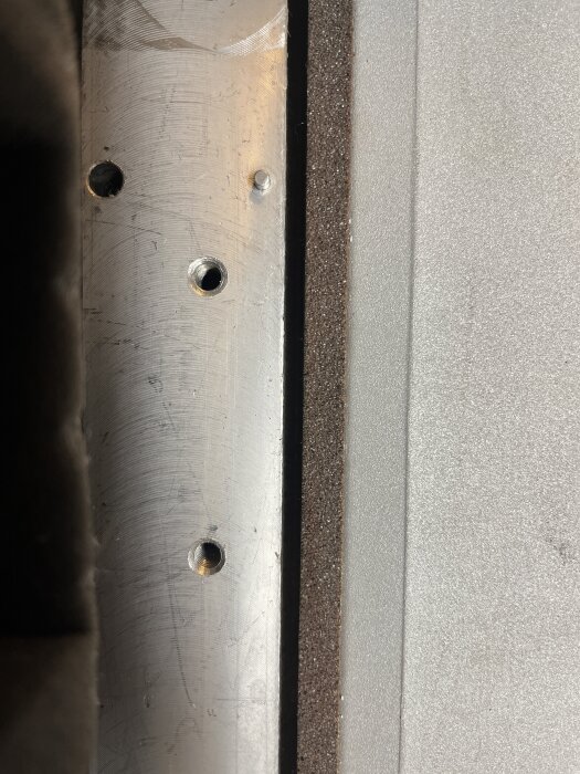 Närbild av en sliten och skadad kutter på en Triton TPT125 hyvelmaskin, med flera små hål i metallen.