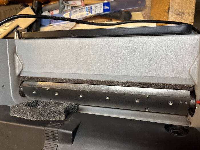 Skadad kutter på Triton TPT125 hyvelmaskin, slitage synligt på kutterskär. Verktyg och tillbehör syns i bakgrunden.