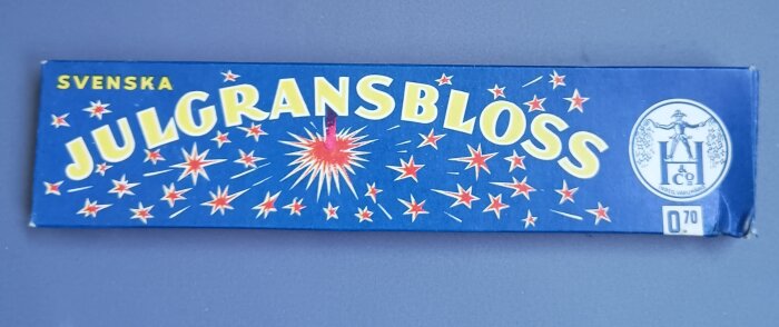 Blå förpackning med texten "Julgransbloss", dekorerad med röda stjärnor och en logotyp, pris 0,70 öre.