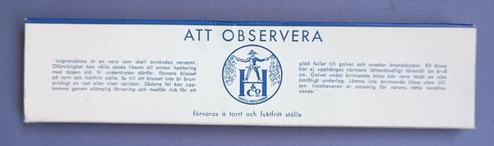 Förpackning av julgransbloss med varningstext och instruktioner för säker hantering, märkt "ATT OBSERVERA".