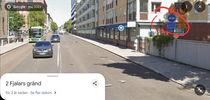 Gata i Uppsala med bilar och buss, vägskyltar synliga på en fasad, omgivna av byggnader och trottoarer.