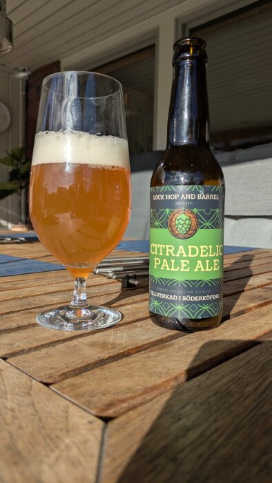 Flaska och glas med Citradelic Pale Ale från Söderköping på ett bord.