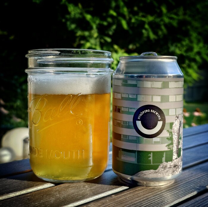Burk och glas med Nyköpings lager på ett bord utomhus.
