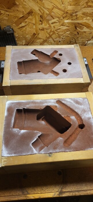 Formar för gjutning i sand av aluminiumdelar på en träbänk.