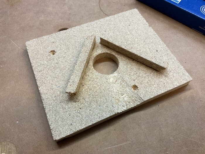 Hemmagjort mätinterface av spånskiva med ett hål och vinkel, använd för att centrera anemometern vid mätning av luftflöde från en dammsugare.