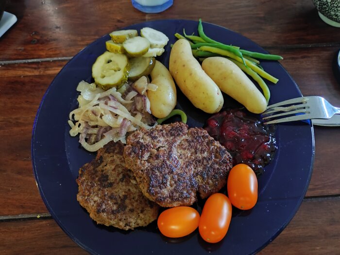 Tallrik med kalvfÀrsbiffar, potatis, sylt, lök, gurka, gröna bönor och tomater; allt utom fÀrsen Àr frÄn egen tomt och skog.