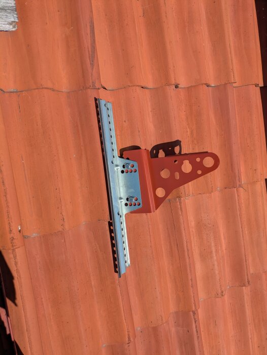 Nockräcke i metall monterat på tak med röda takpannor.