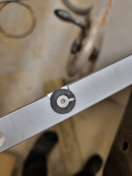 Närbild på en metallskena med justerbricka synlig, i en verkstads- eller byggmiljö.