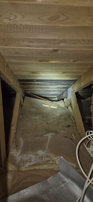 Kallvind med träbjälkar och svarta plankor som kan indikera en potentiell läcka, trots att fuktmätning visar torra värden.