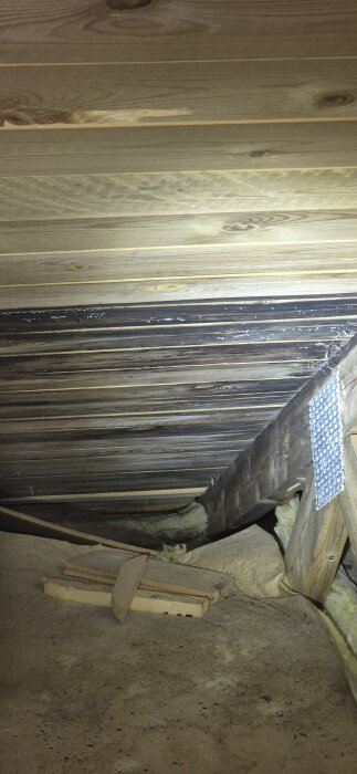 Svarta plankor i taket på en kallvind, potentiella tecken på tidigare fuktproblem eller mögel, inspektion av besiktningsman rekommenderas.