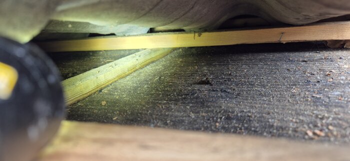 Svarta plankor på kallvinden, eventuellt fuktskadade, ses i detalj. Mögel och torrt virke synligt. Möjlig läcka utvärderas.