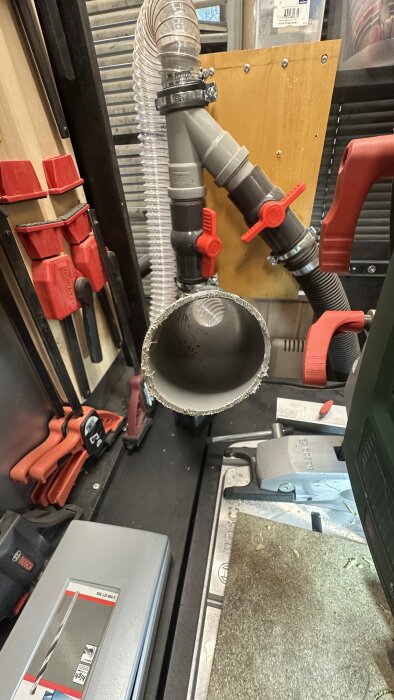 Närbild på ett cyklonsystem med 50 mm avloppsrör, slangar och ventiler monterat på en vägg i en verkstad.