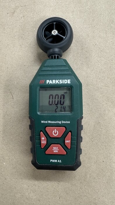 Anemometer av märket Parkside med digital display som visar vindhastighet och temperatur, placerad på en brun yta.