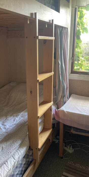 Löstagbar trässtege bredvid en loftsäng, konstruktion gör den vinklingsbar och avtagbar. Bred design med funktionella steg, placerad vid sängkant.