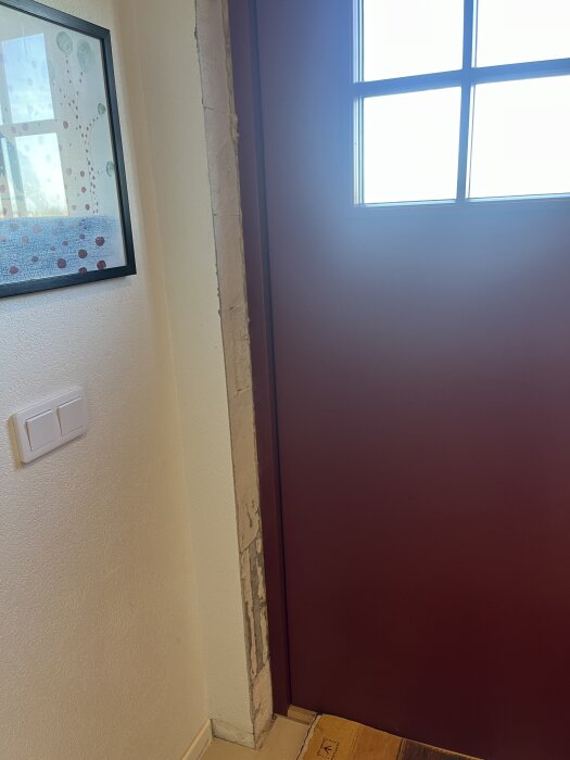 Dörr med putsad vägg av siporexblock på vänster sida, delvis exponerad vid dörrens kant. Väggströmbrytare och tavla är synliga.