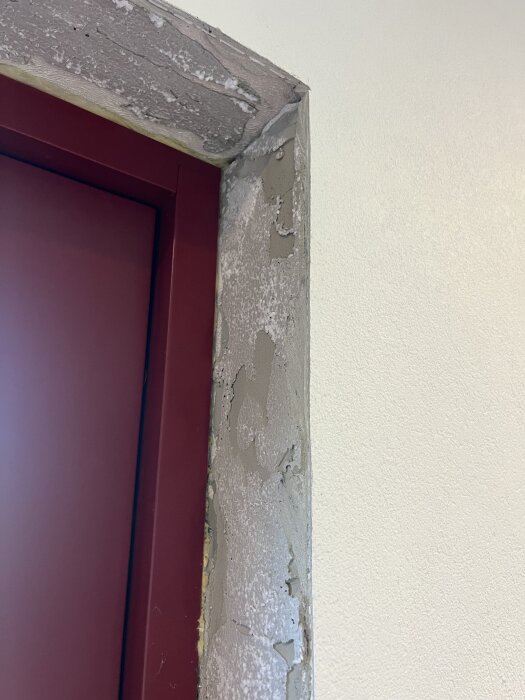 Dörrkarm med ojämn yta av puts på siporexblock, del av vägg syns. Fråga om återställning av dörrhål efter utvidgning.