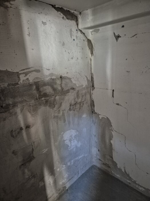 Sprucken innervägg i källare med plåster och avskalad puts, visar gammal skada efter rivning av felaktigt byggd bastu.