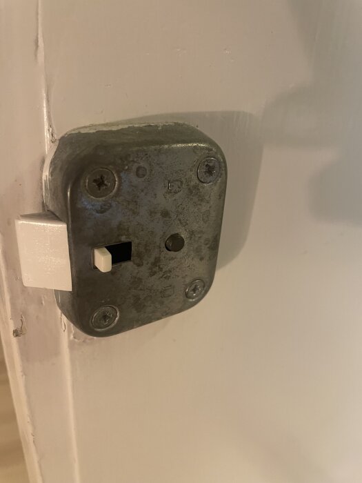 Dörr utan handtag med gammalt metallplatta, saknar vred på insidan.