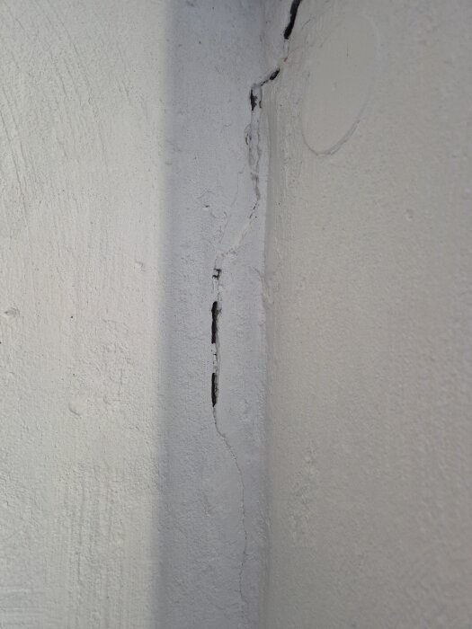 Spricka i vitmålad vägg i en källare.