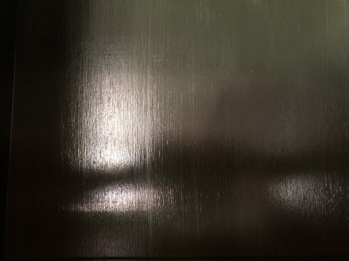 Närbild på plywood med furu och linolja, där ådring och penseldrag syns tydligt på den blanka och lätt ådrade ytan.