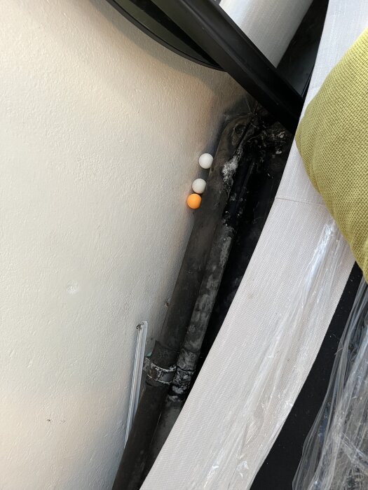 Svarta rör med mögelliknande fläckar i ett garage från 1939. Tre pingisbollar i vitt och orange ligger bredvid rören. Ingen lukt upplevs.