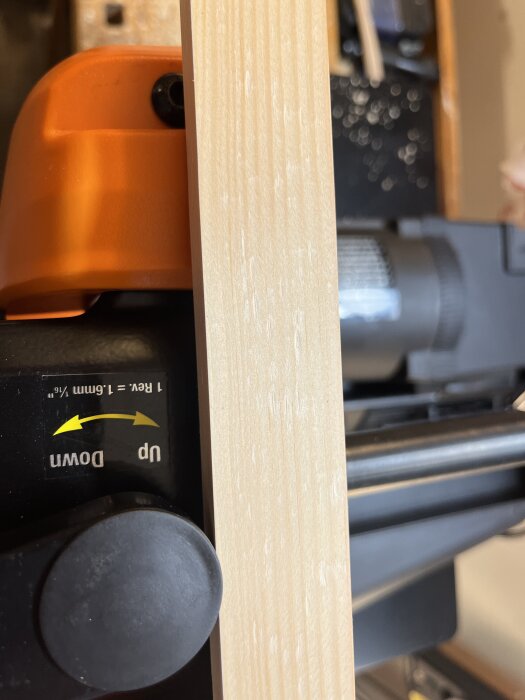 Brädbit av furu efter bearbetning, synlig på en hyvel med del av dess justeringsmekanism och skalor, potentiellt behöver bladen bytas ut.