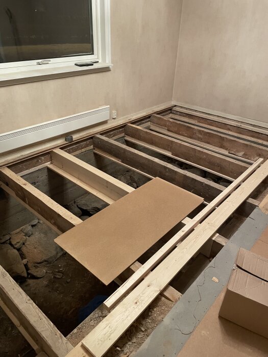 Renovering av ett rum med synliga golvbjälkar, nya reglar och en bräda på golvet. Förberett för byte av syll och bärlina.