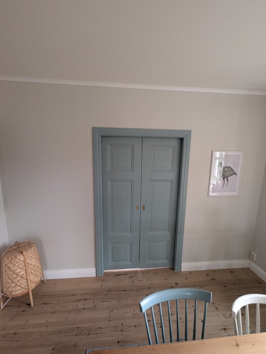Blå skjutdörrar i ett rum med trägolv och en korgkorg som står bredvid.