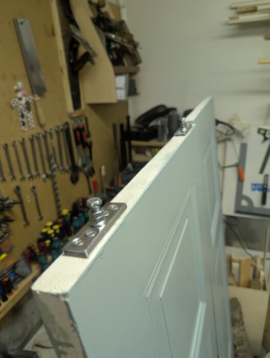 Skjutdörr med monterat Habo K-40 beslag i en verkstad. Dörren är slipad och målad, omgiven av verktyg och hyllor.