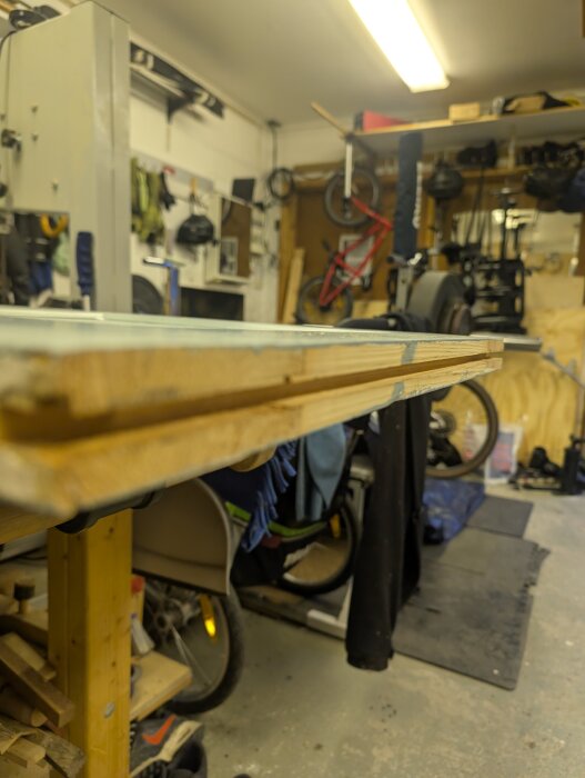 Träverkstad med dörrblad redo för målning, spår fräst undertill för skjutdörrsbeslag, cykel och verktyg i bakgrunden.